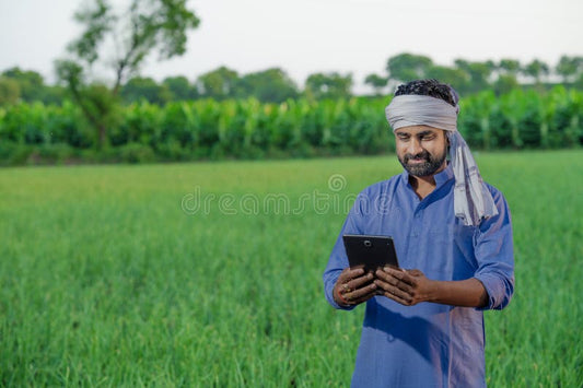 Indian farmer using tablet for crop monitoring on field