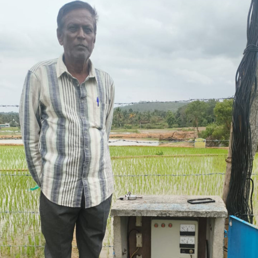 Man standing next to a small structure with electronic components in a field